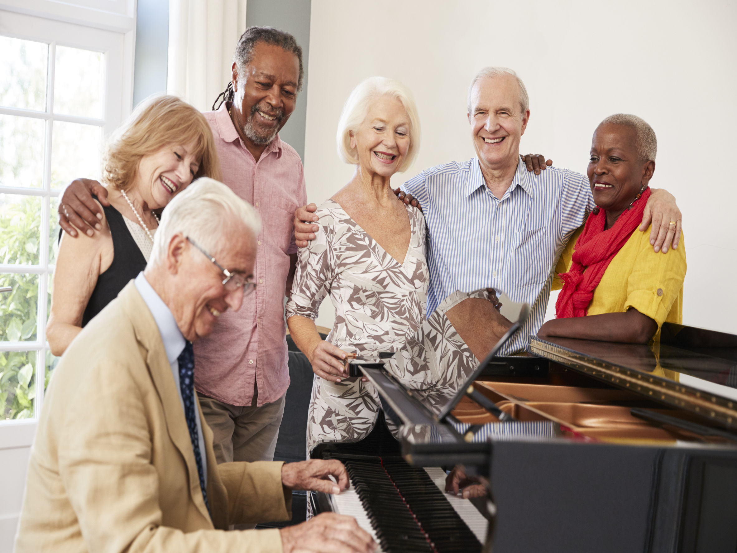 Grupo de jubilados tocando el piano y cantando